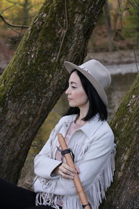 Woman standing by tree trunk