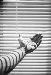 Cropped hand against blinds