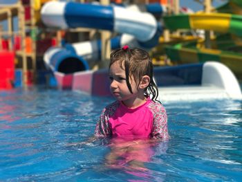 Girl looking away while swimming in pool at water park