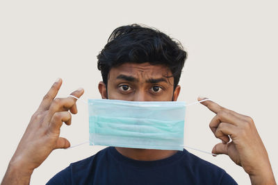 Portrait of young man making face against white background