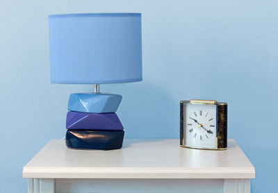 View of lamp with clock on table against wall