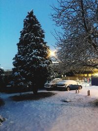 Snow covered road by trees against sky