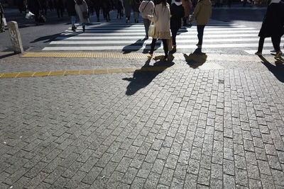 Low section of people walking on city street