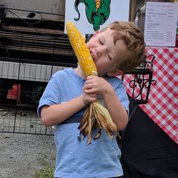 Close-up of boy eating corn while standing outdoors