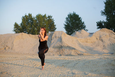 Confident mature woman practicing yoga on land during sunrise