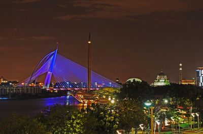 Seri wawasan bridge over river against sky in city at night