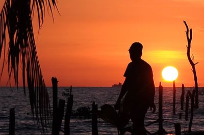 Silhouette man standing at beach during sunset