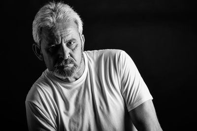 Portrait of man sitting against black background