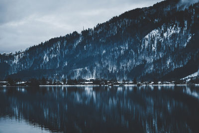 Scenic view of lake by snowcapped mountain against sky