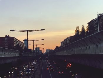 Cars on illuminated city against sky during sunset