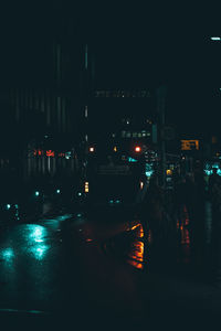 Illuminated street amidst buildings in city at night