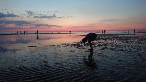 Silhouette man standing on beach against sky during sunset