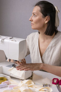 Side view of woman using sewing machine