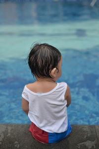 Rear view of baby sitting by pool