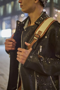 Midsection of young man standing in city at night