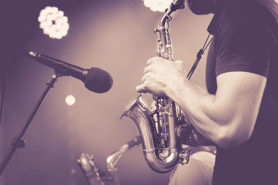 Midsection of man playing saxophone on stage