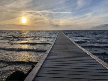 Pier over sea against sky during sunset