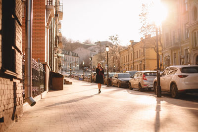 Young woman walking on city street on sunny day