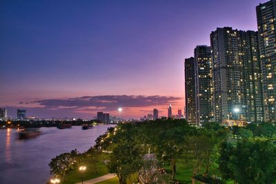 Illuminated buildings in city against sky at sunset