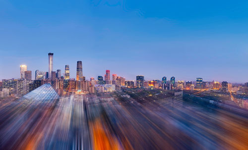 Blurred motion of city buildings against blue sky