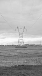 Electricity pylon on field against sky