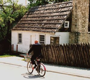 Man riding bicycle on house by building
