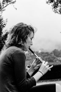 Side view of senior man playing music against sky