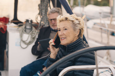 Senior woman talking on mobile phone while sitting by man in yacht