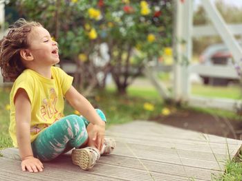 Girl looking away while sitting outdoors