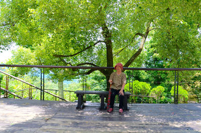 Full length of woman sitting on bench against railing