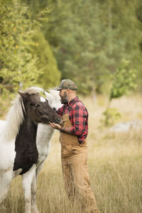 Male farmer stroking horses in field