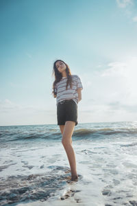 Full length of young woman standing on beach