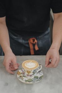 Midsection of woman with coffee cup on table