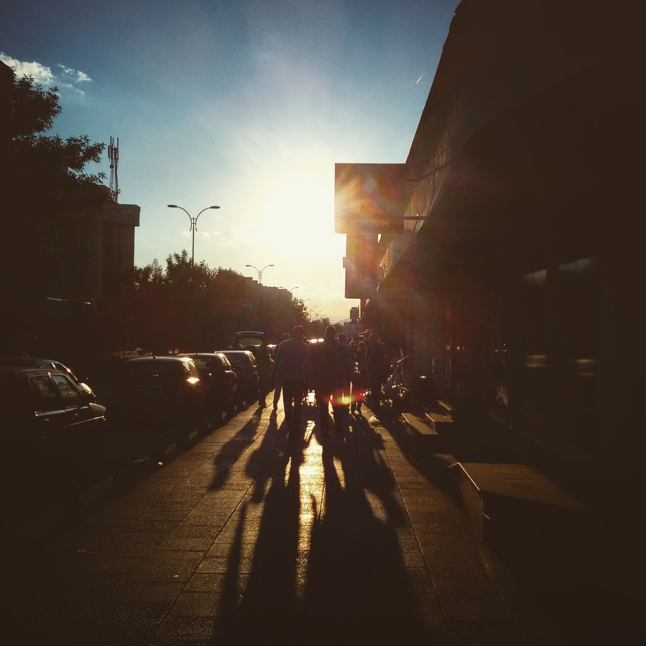 building exterior, architecture, built structure, transportation, the way forward, city, street, car, road, sunlight, sky, land vehicle, diminishing perspective, sun, mode of transport, vanishing point, building, sunset, city street, city life