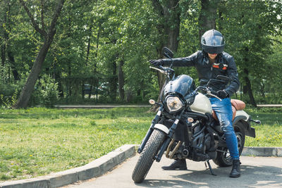 Man riding motorcycle on road against trees