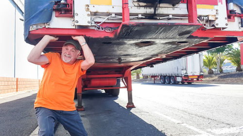 Portrait of senior man carrying truck on road