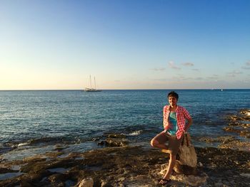 Portrait of man standing on rock at beach against sky