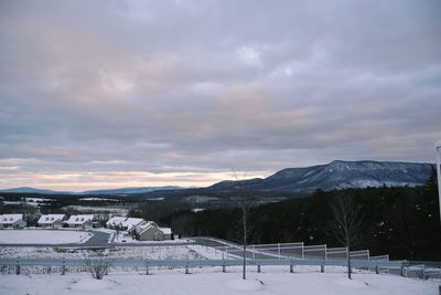 Snow covered field against sky during sunset