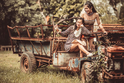 Female friends on abandoned vehicle at field