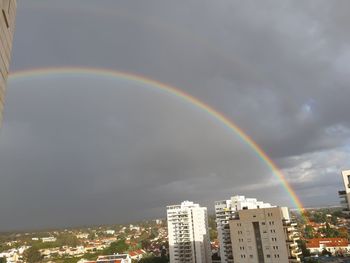 Rainbow over buildings in city against sky