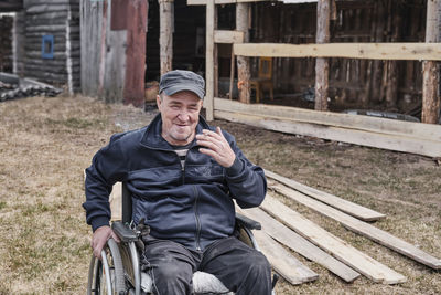 Portrait of happy senior man in wheelchair in yard of his house smiling. a cigarette in his hand.