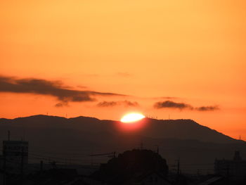 Scenic view of silhouette mountains against orange sky