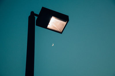 Low angle view of illuminated lamp against blue sky