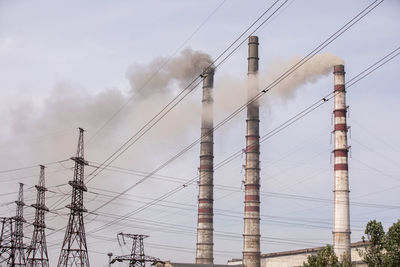 Power plant is creating energy for the people. high voltage post. smoke from the chimneys against 