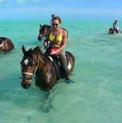 Woman sitting on horse in sea