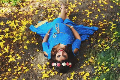 Portrait of happy boy lying on leaves during autumn