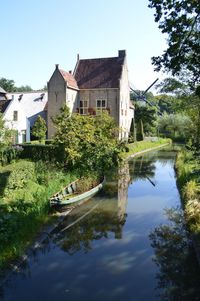 Houses by lake and buildings against sky