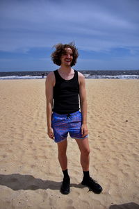 Portrait of woman standing at beach against sky