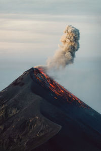 View of smoke emitting from volcanic mountain against sky