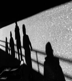 Silhouette people standing against illuminated shadow